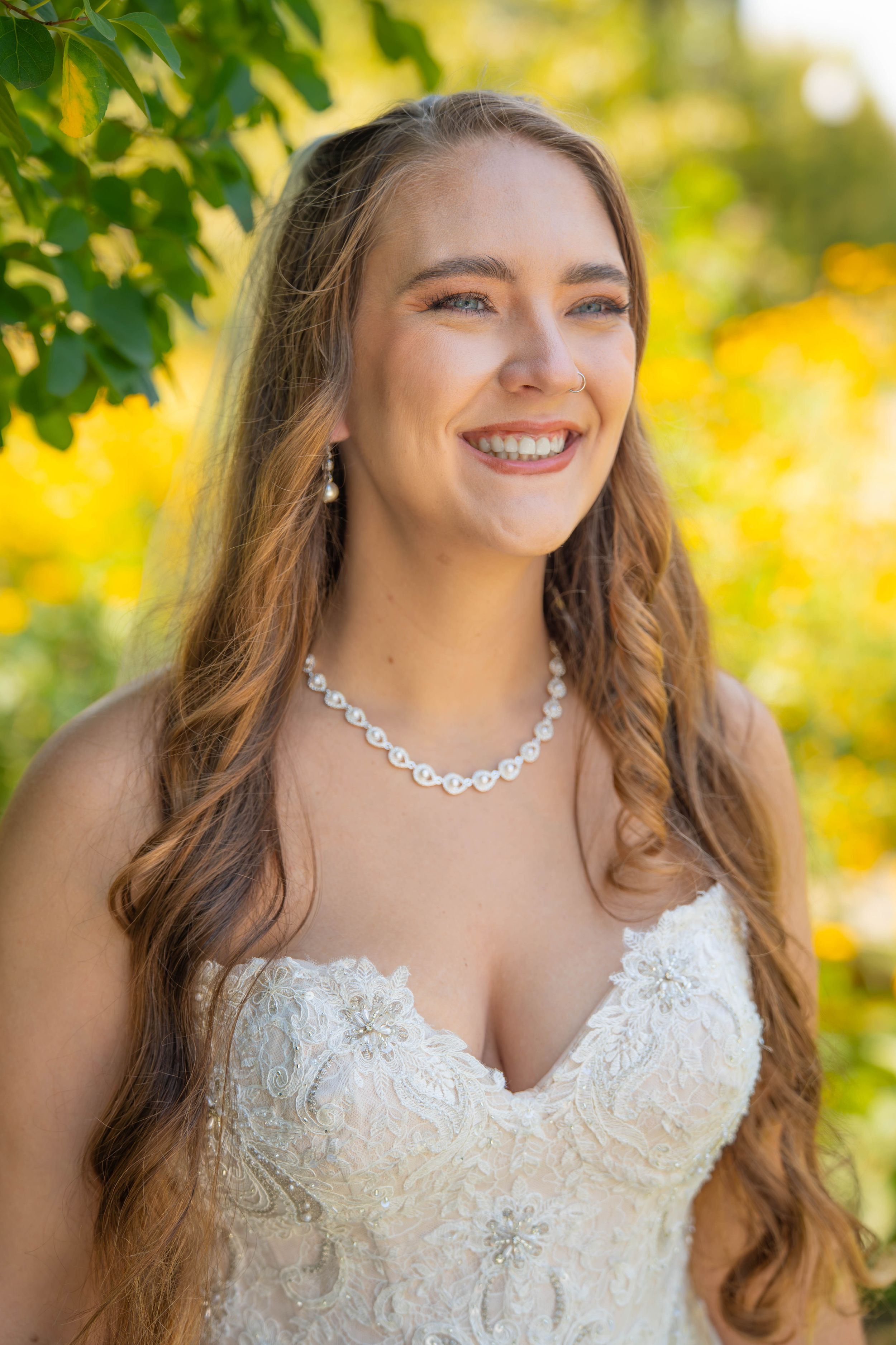 Close-up portrait series of a person in a white lace wedding dress with a delicate necklace against autumn foliage.