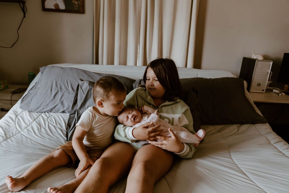 Intimate lifestyle photography showing gentle moments with a baby on white bedding.