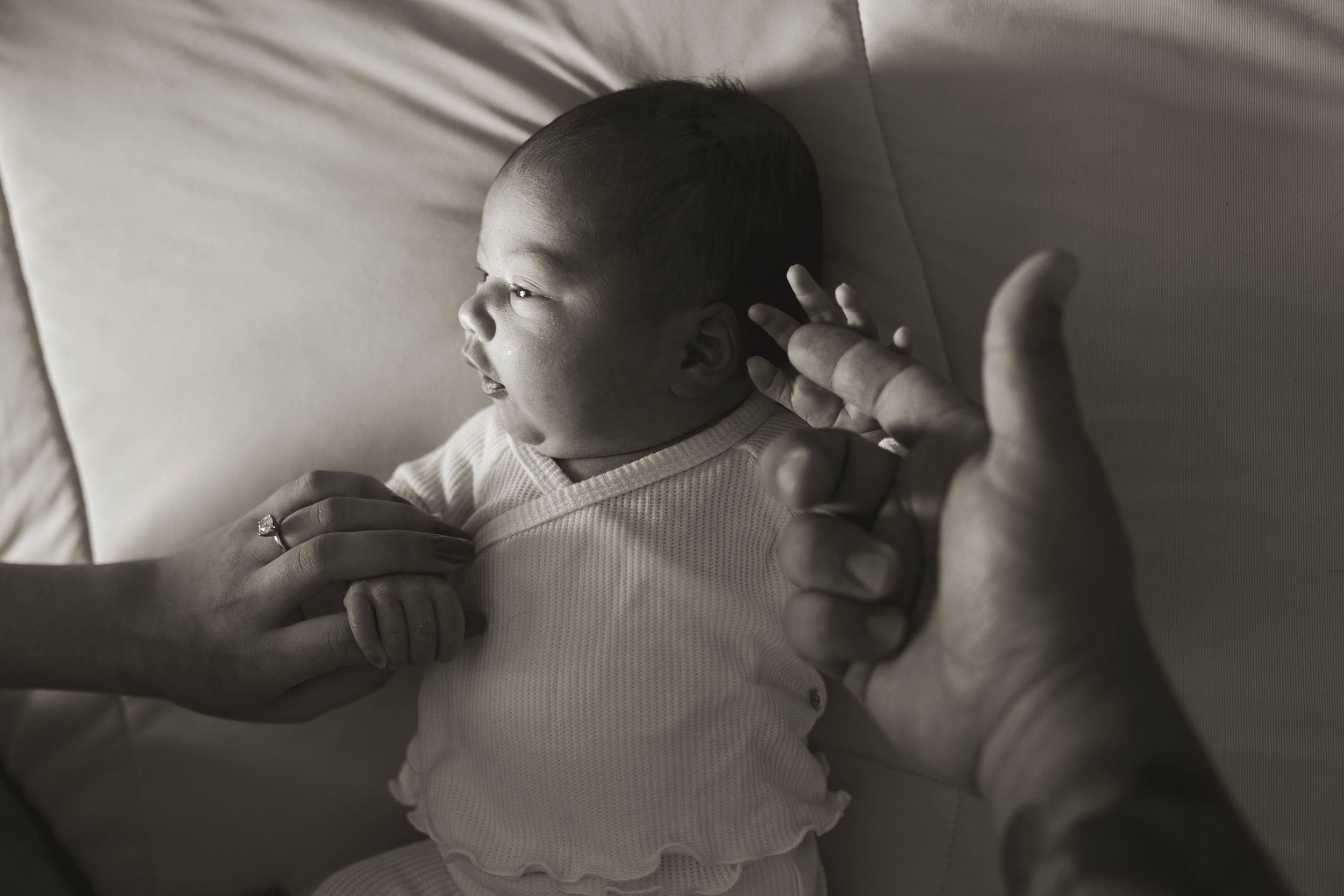 Artistic black and white photograph showing tiny baby feet against white bedding.