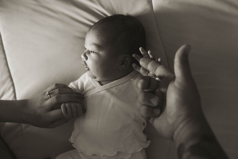 Artistic black and white photograph showing tiny baby feet against white bedding.