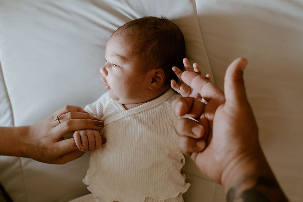 Gentle hands cradling a newborn baby in soft natural light.