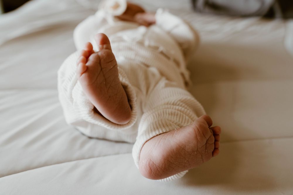 Close-up detail of tiny newborn feet against white linens.