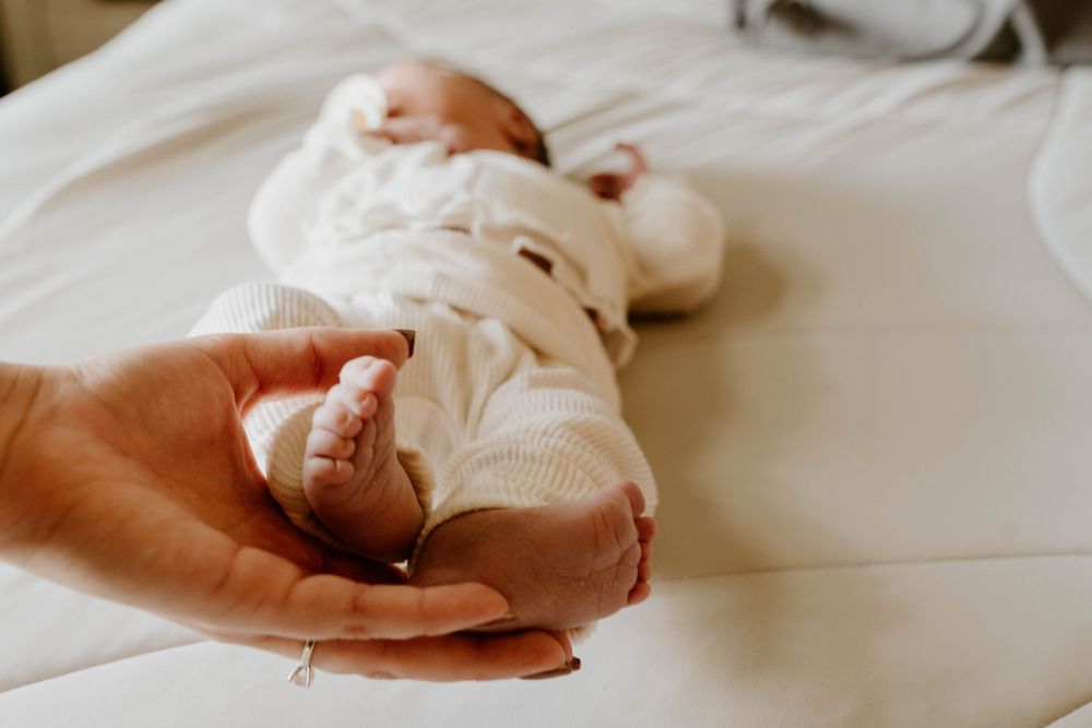 Delicate black and white image of hands holding a sleeping baby.