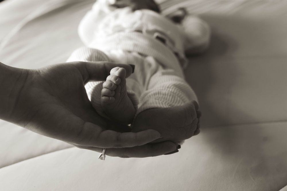 Artistic black and white photograph of hands supporting a newborn.