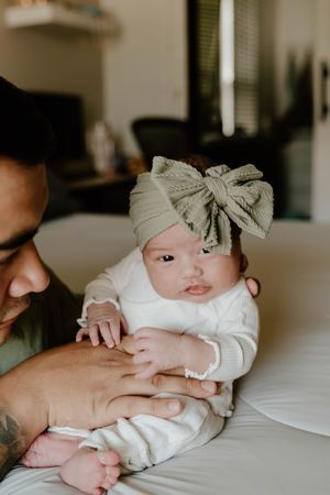 Newborn baby wearing a bow headband during an intimate lifestyle photoshoot.