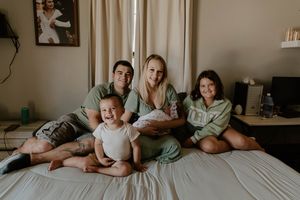 Candid family photo session showing relaxed moments on a bed.