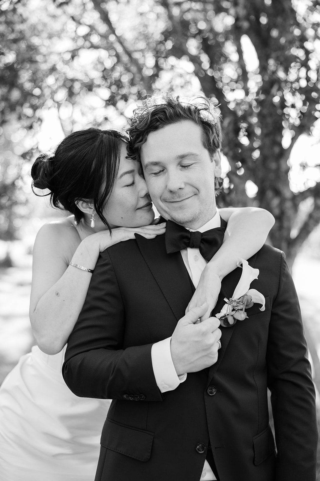 A couple in formal black and white attire share intimate moments in a romantic outdoor photo series.
