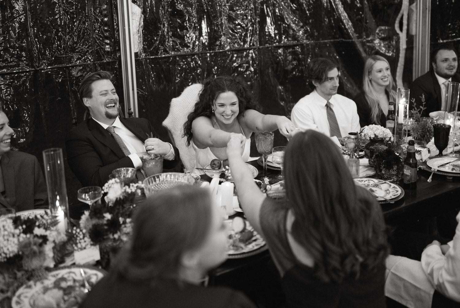 Wedding reception guests sharing laughter at an elegantly decorated dinner table.