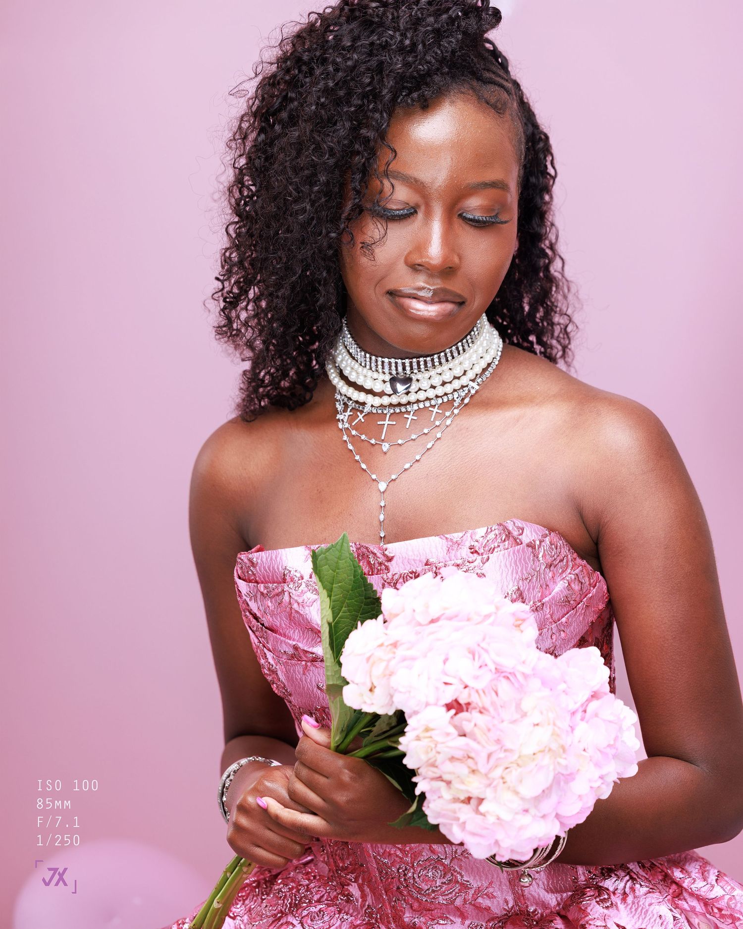 Elegant portrait against pink background featuring ornate silver necklace and pink peonies in a romantic styled photoshoot.