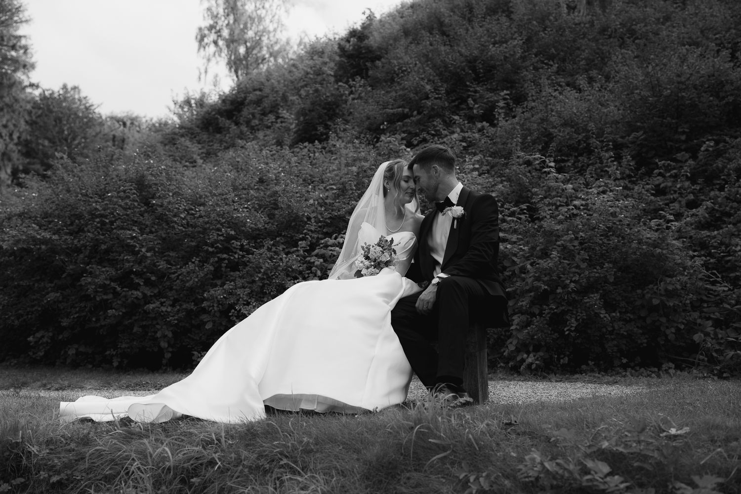 A black and white wedding photo collage showing romantic moments between newlyweds in an outdoor garden setting.