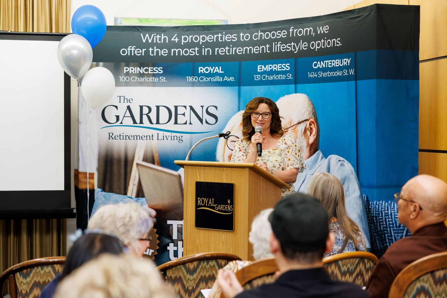 Attendees view a presentation about retirement living options with balloons decorating the space.