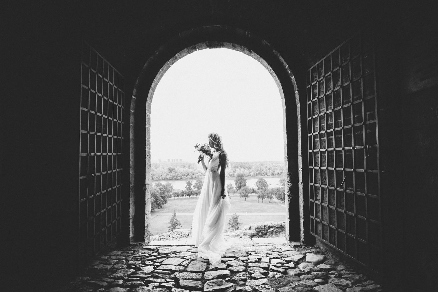 A black and white photograph shows a stone tunnel entrance with light streaming through the arched opening.