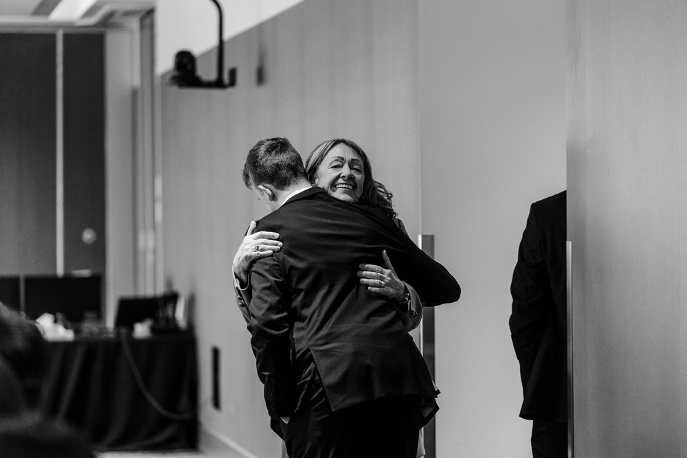 Two people share a joyful embrace in a hallway, captured in black and white photography.
