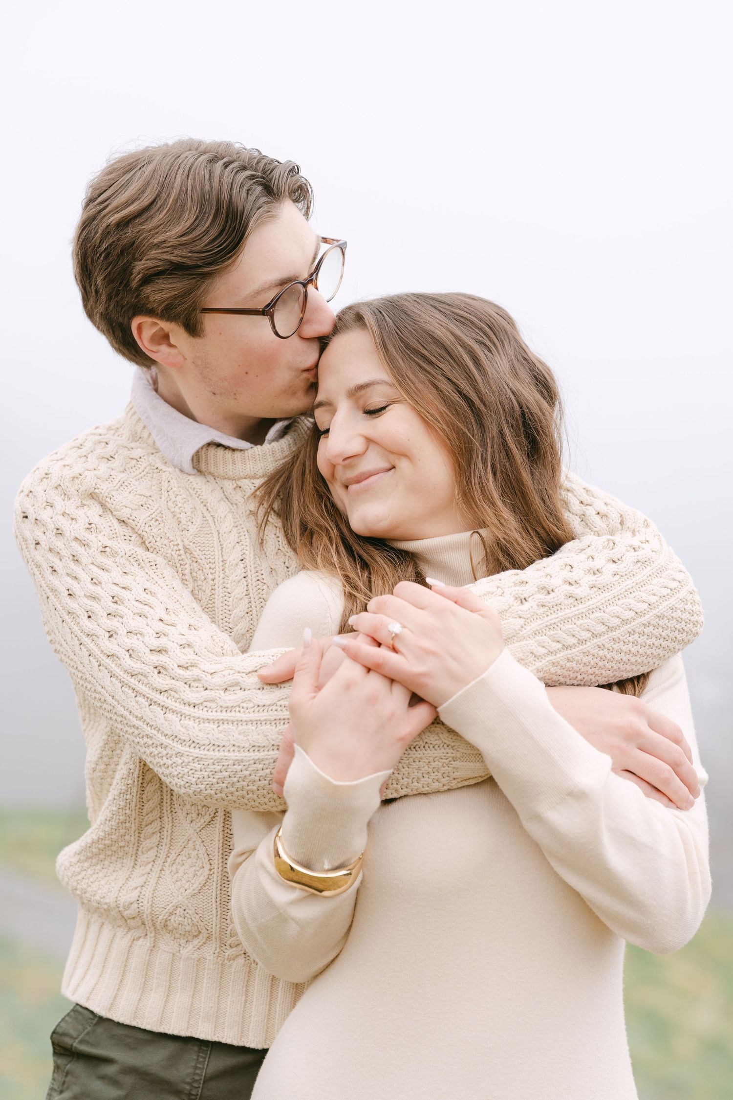 A romantic couple in cream sweaters embrace tenderly in a series of intimate outdoor photos.