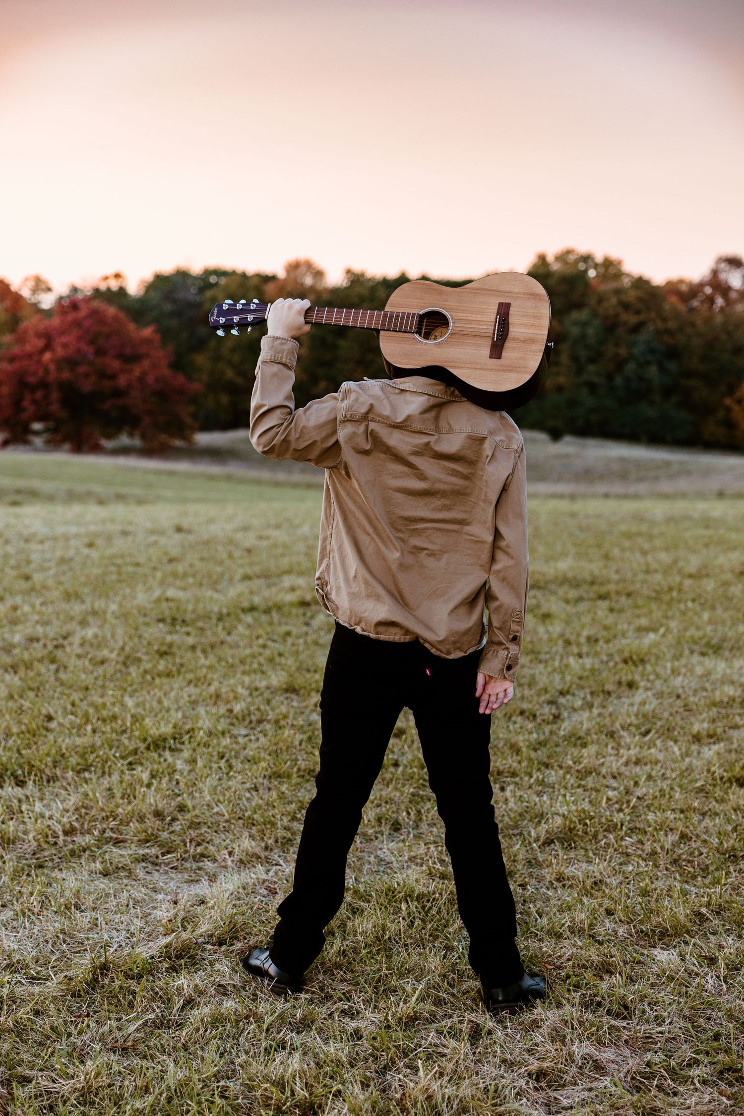Three artistic photos of a person holding an acoustic guitar in a grassy field at sunset.