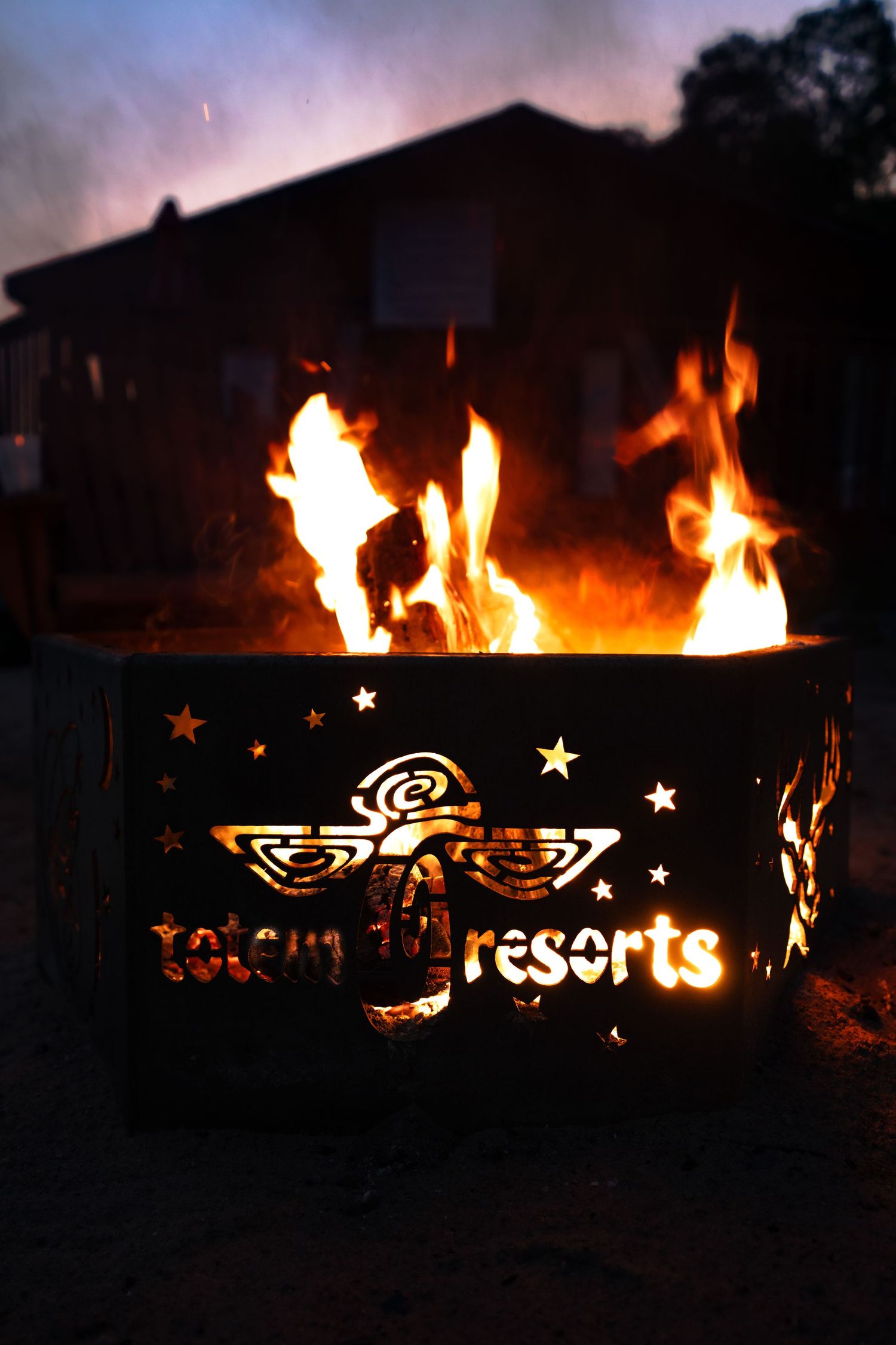 Custom metal fire pit displaying illuminated text and designs at night.