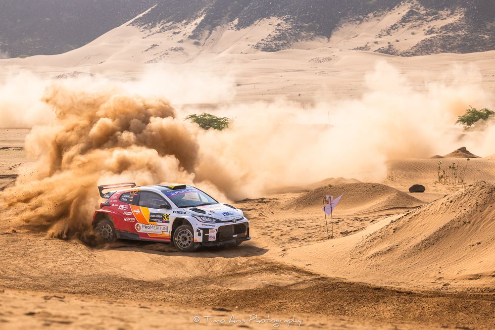 Rally cars kick up dust clouds while racing through desert terrain during an off-road competition.