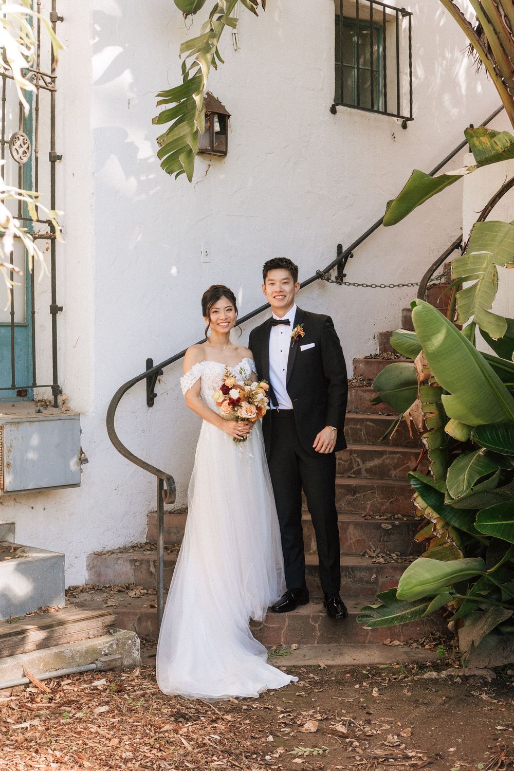 A bride and groom stand on the stairs at the Santa Barbara Courthouse for wedding photos by a Santa Barbara Photographer