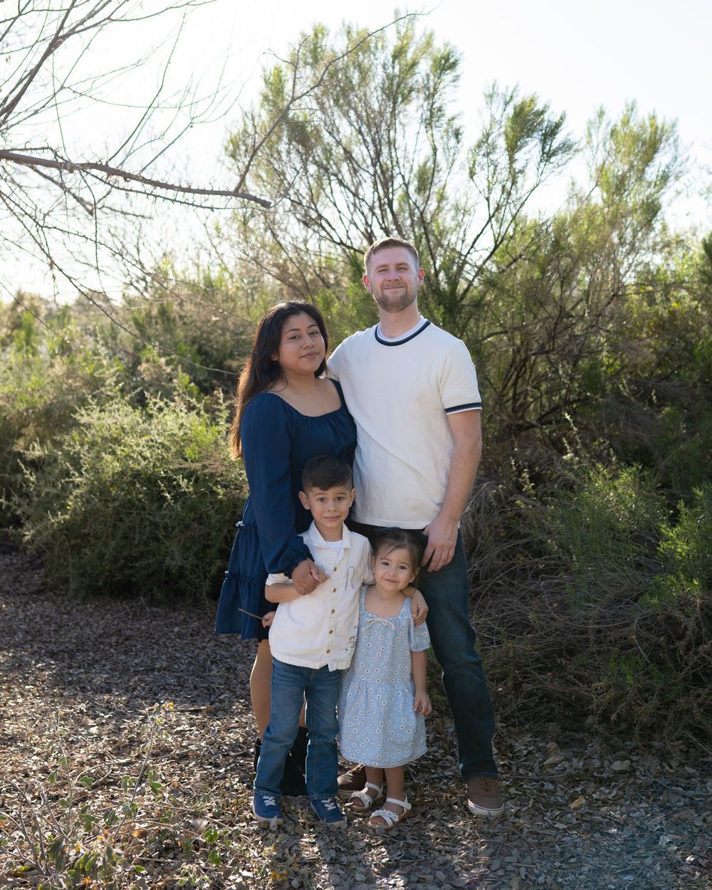 A family poses together for portraits against a natural desert landscape background.
