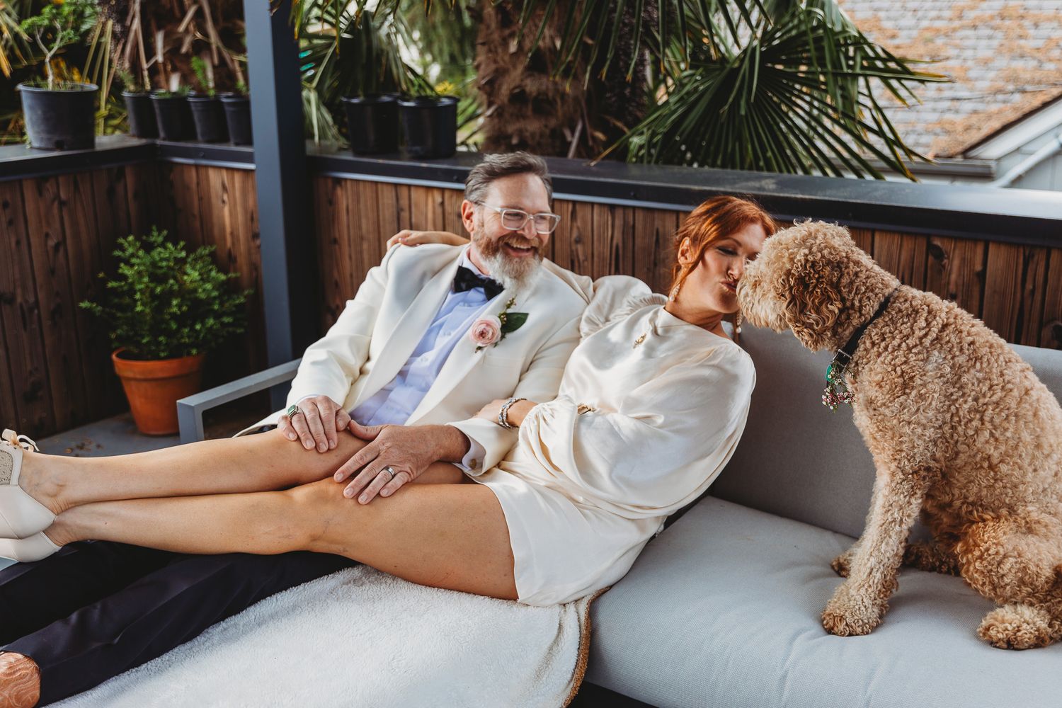 Person relaxing on outdoor furniture with goldendoodle dog on sunny patio.