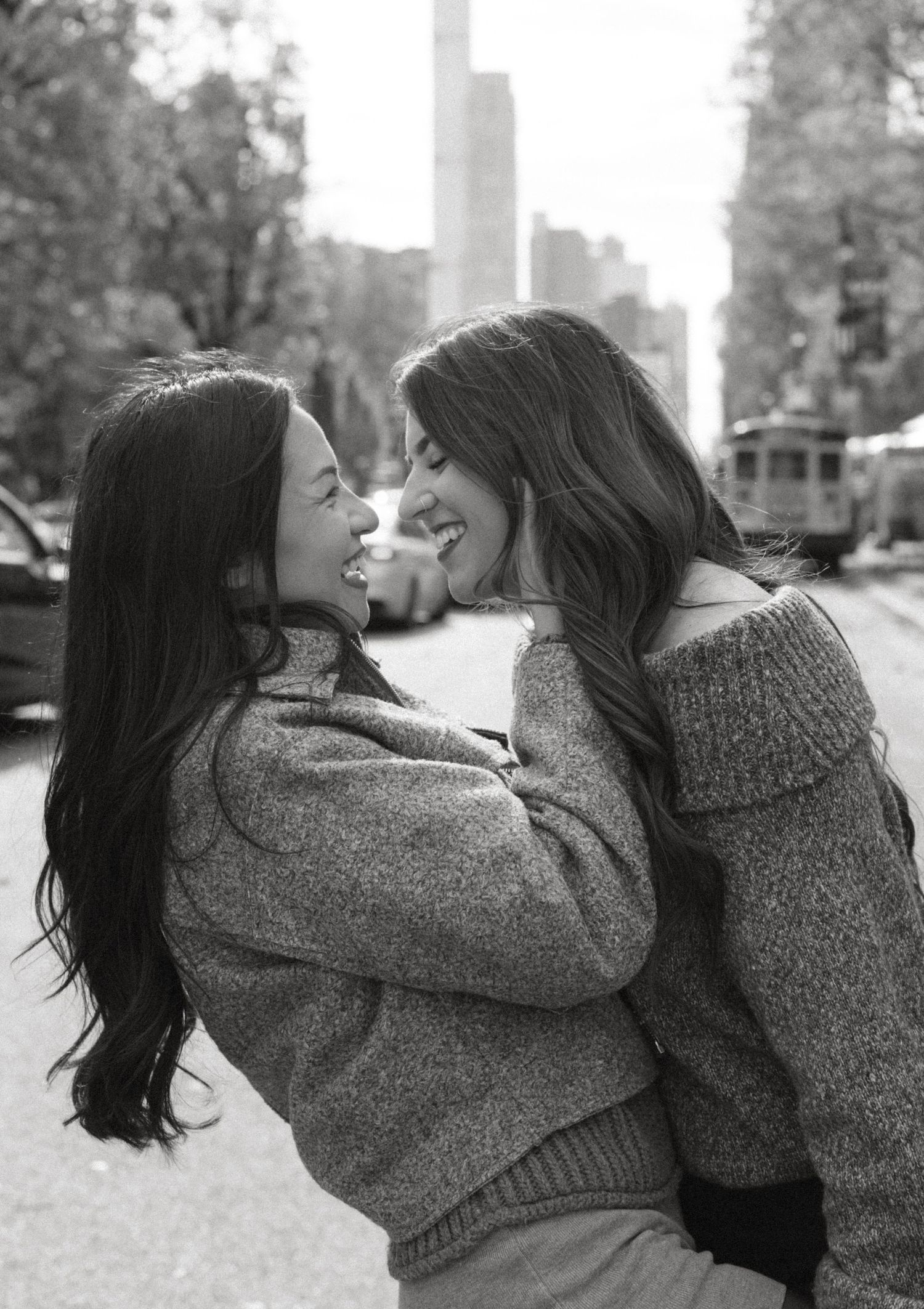 Friends sharing intimate playful moments in matching sweaters outdoors.