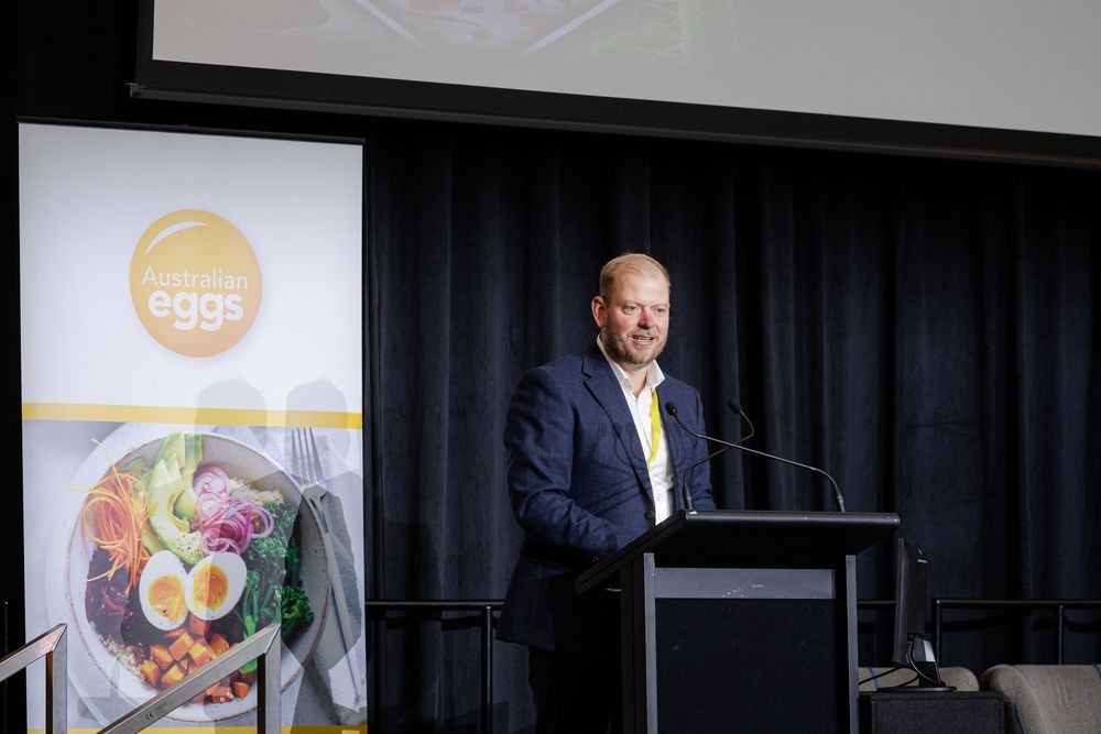 A person in a suit gestures while speaking at a podium, photo captured by Fremantle Conference Photographer