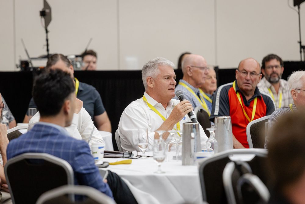 Business professionals seated at round tables during a conference event. Fremantle Conference Photographer