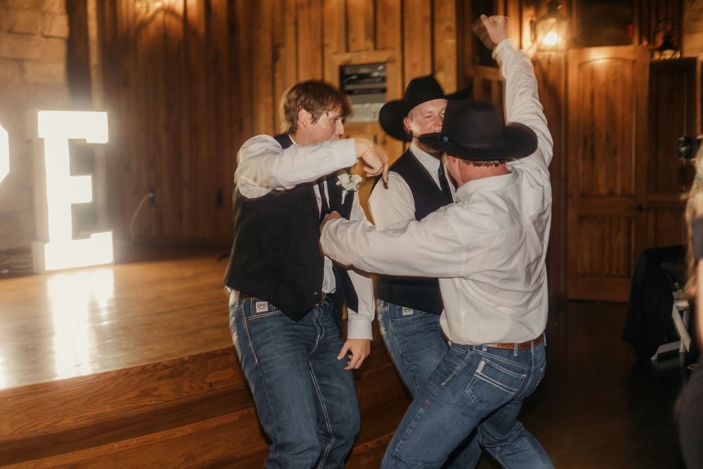 People dancing and having fun at a rustic venue with wood paneling and illuminated wall decor.