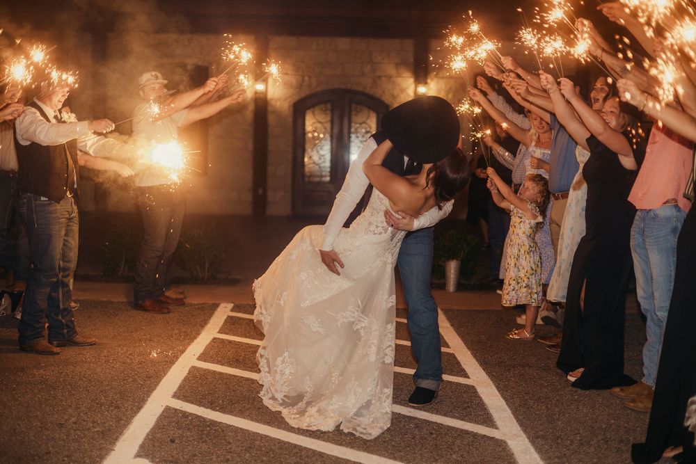 Sparklers illuminate a romantic wedding exit as guests line up to celebrate the newlyweds' departure.