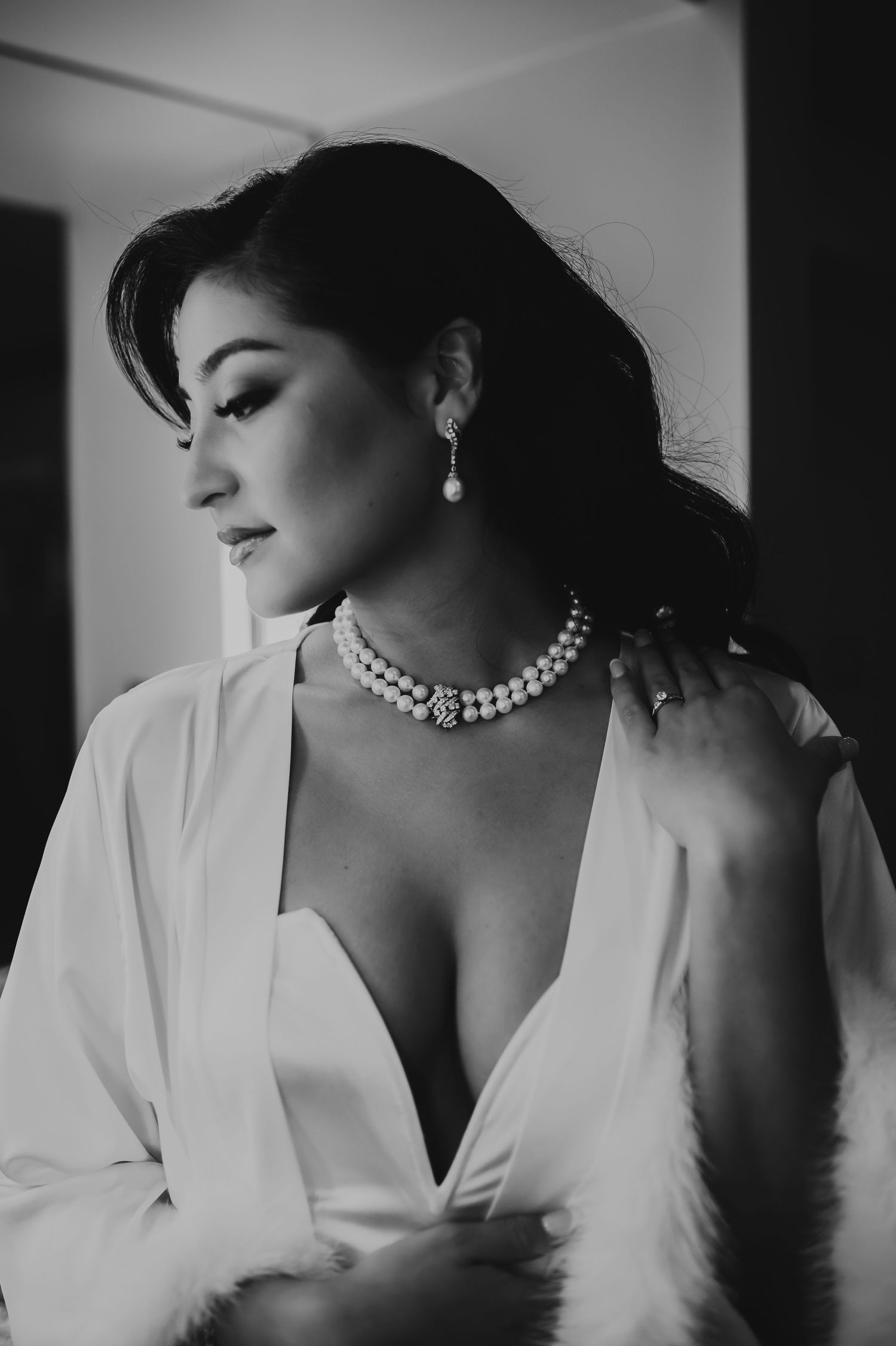 Black and white artistic portrait series of woman in white top and pearl necklace showing different elegant poses.