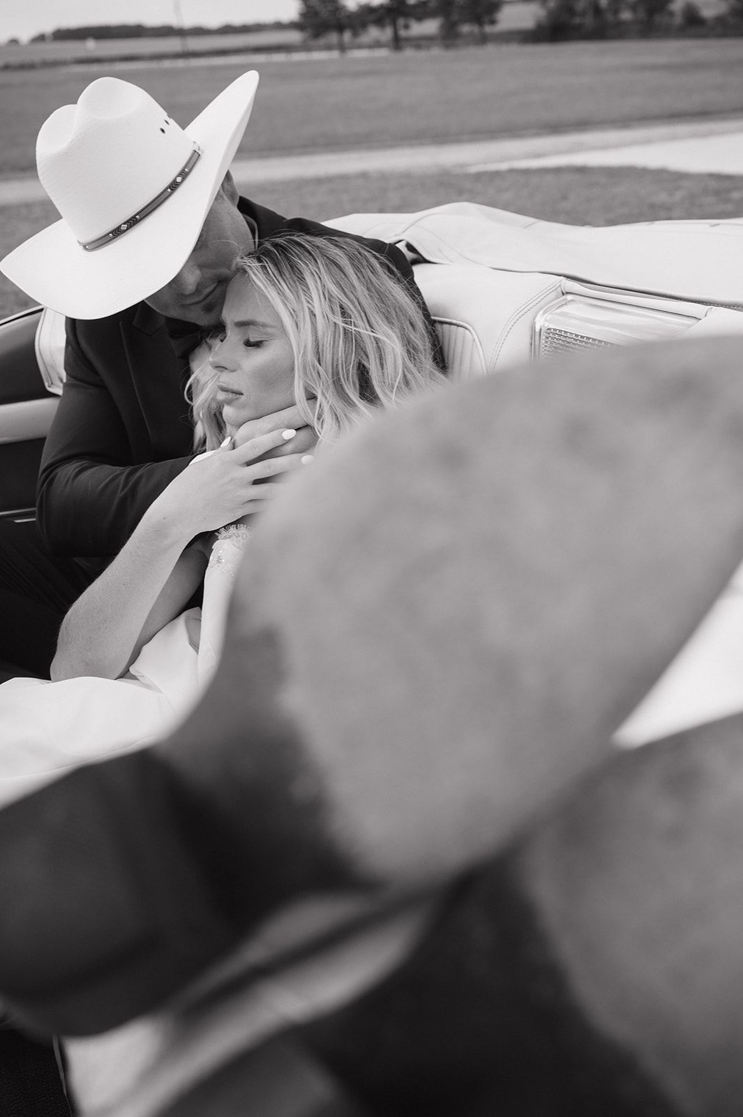 A romantic black and white photo showing an intimate moment between a couple in a convertible vintage Cadillac car.