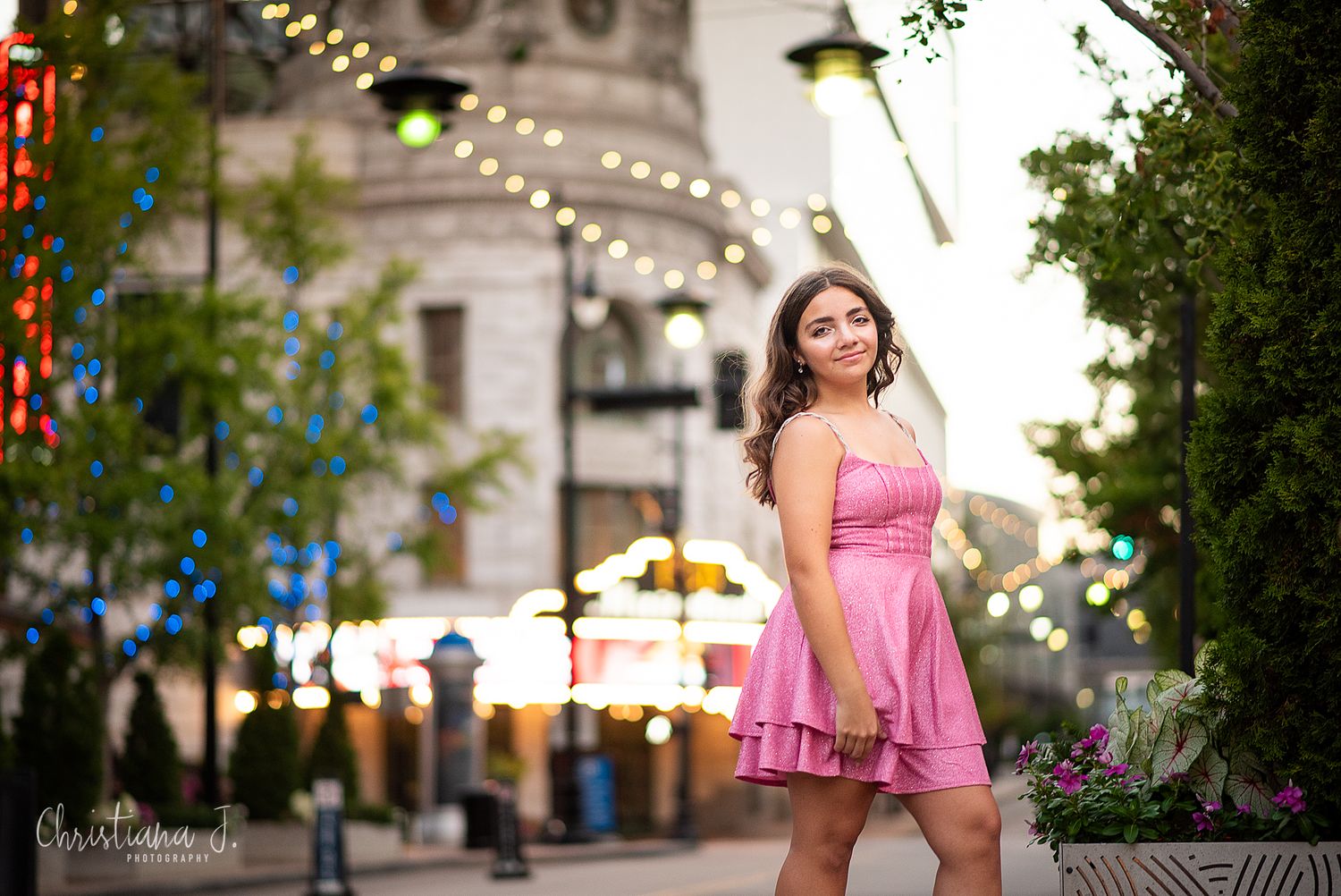High school senior photographer Kansas City, teen in pink dress posing in the power and light district kansas city near city lights