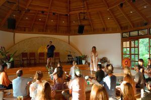 People gathered in a circular wooden dome for a wellness or spiritual workshop.