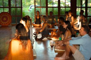 Workshop participants seated on floor mats in a naturally lit studio space.