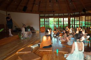 Group gathered in a sunlit wooden hall during a wellness session or workshop.