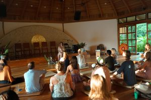 Attendees sitting in circular formation inside rustic dome-ceiling room with large windows.