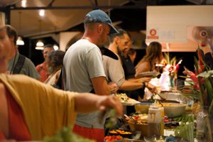 People serving themselves food at buffet table during indoor event.