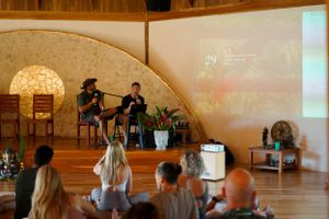 Audience watching presentation in wooden domed room with projection screen.