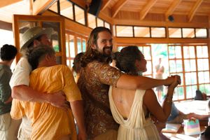 Group of people embracing in circle during indoor workshop or retreat.