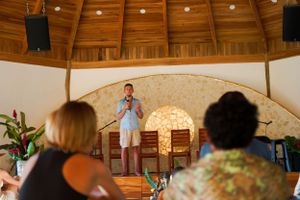 People attending a presentation in a rustic wooden dome structure with exposed beams.