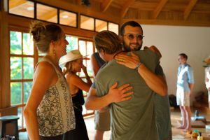 People sharing embraces in a bright indoor gathering space.