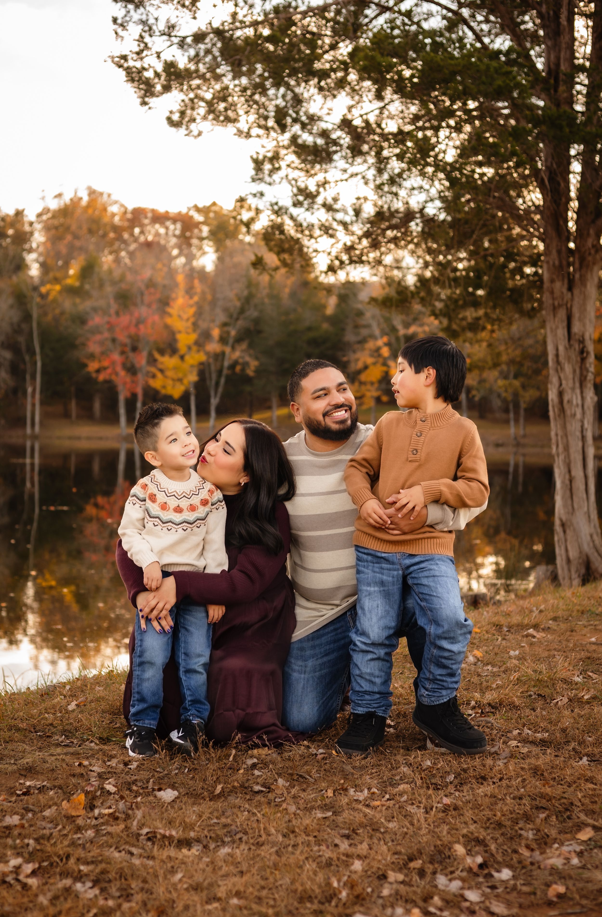 Family, dressed in cozy sweaters and henley embrace against a colorful fall backdrop, captured by Charlottesville family photographer.