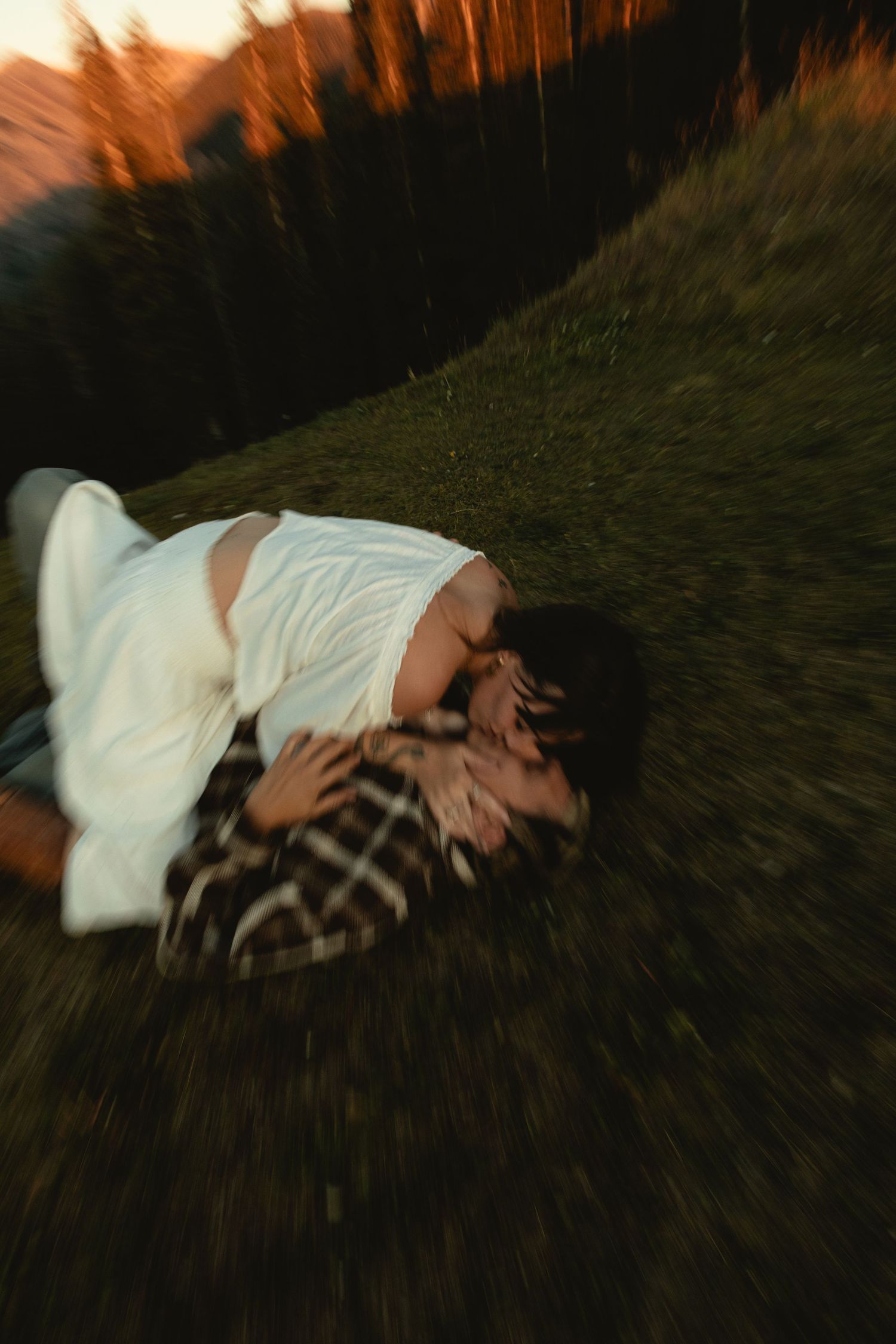 couple rolling around on the ground for a candid kiss