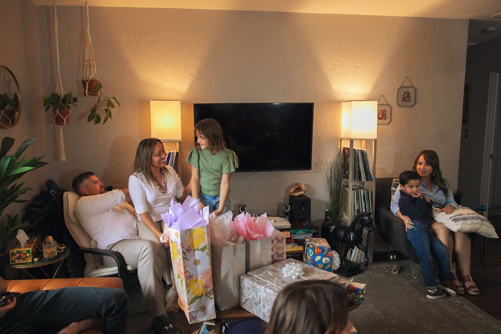College students study and relax together in a cozy dorm room with soft lighting and scattered textbooks.