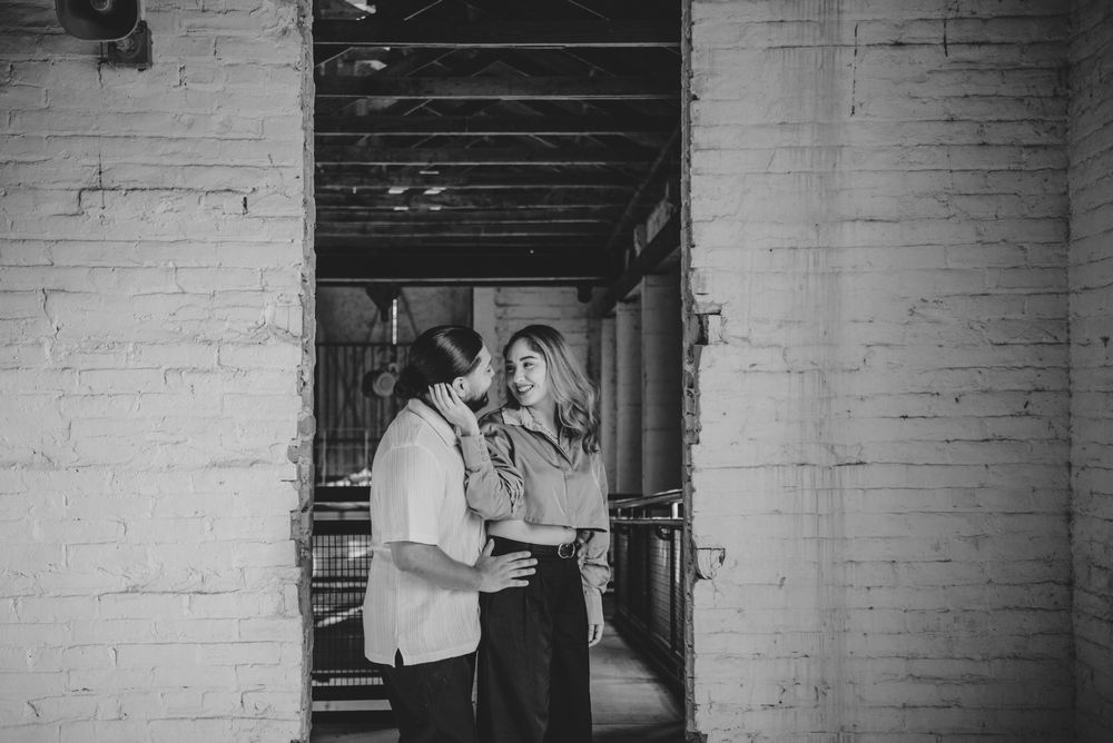 A romantic black and white moment between a couple sharing an intimate connection in an industrial hallway.