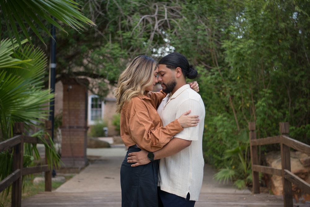 A couple shares intimate moments along a tropical garden path lined with palm trees and lush vegetation.