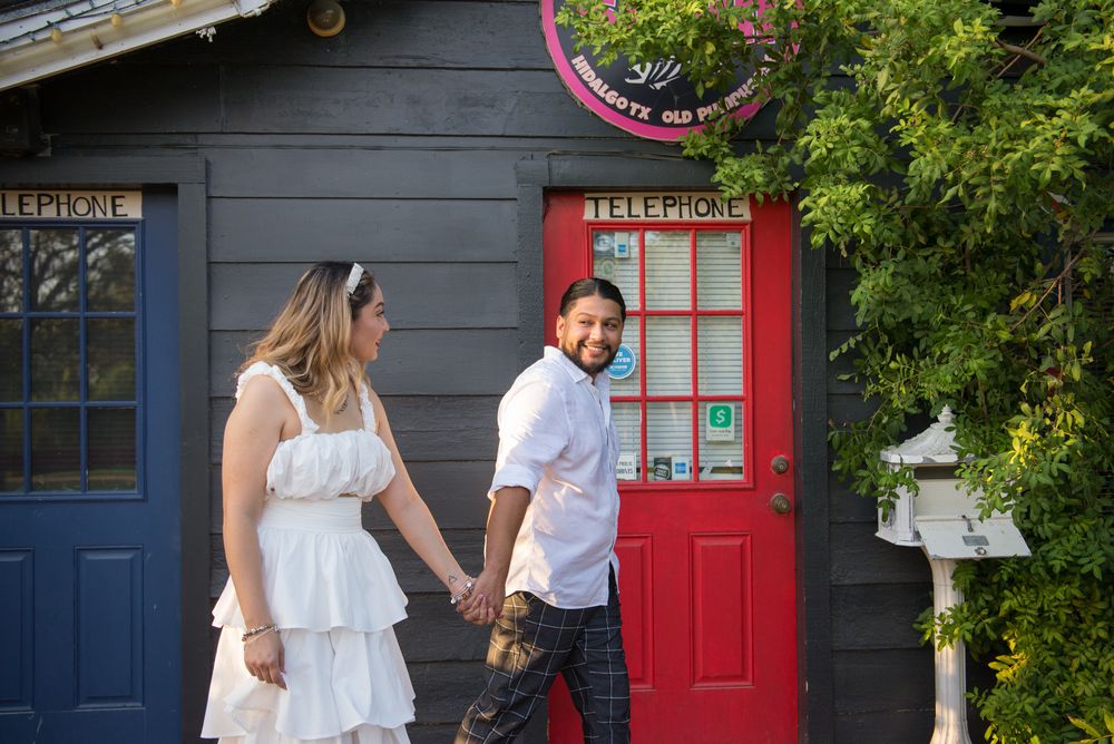 A couple walks together along a colorful line of building facades decorated with blue and red painted doors.