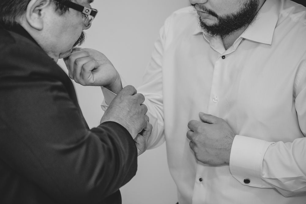 A black and white photo shows someone lighting a cigarette for another person while they stand close together.