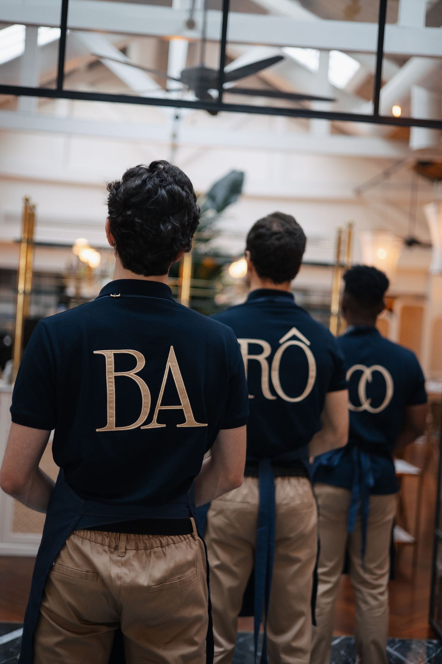 Staff members in dark uniforms display text spelling 'DA' across their backs.