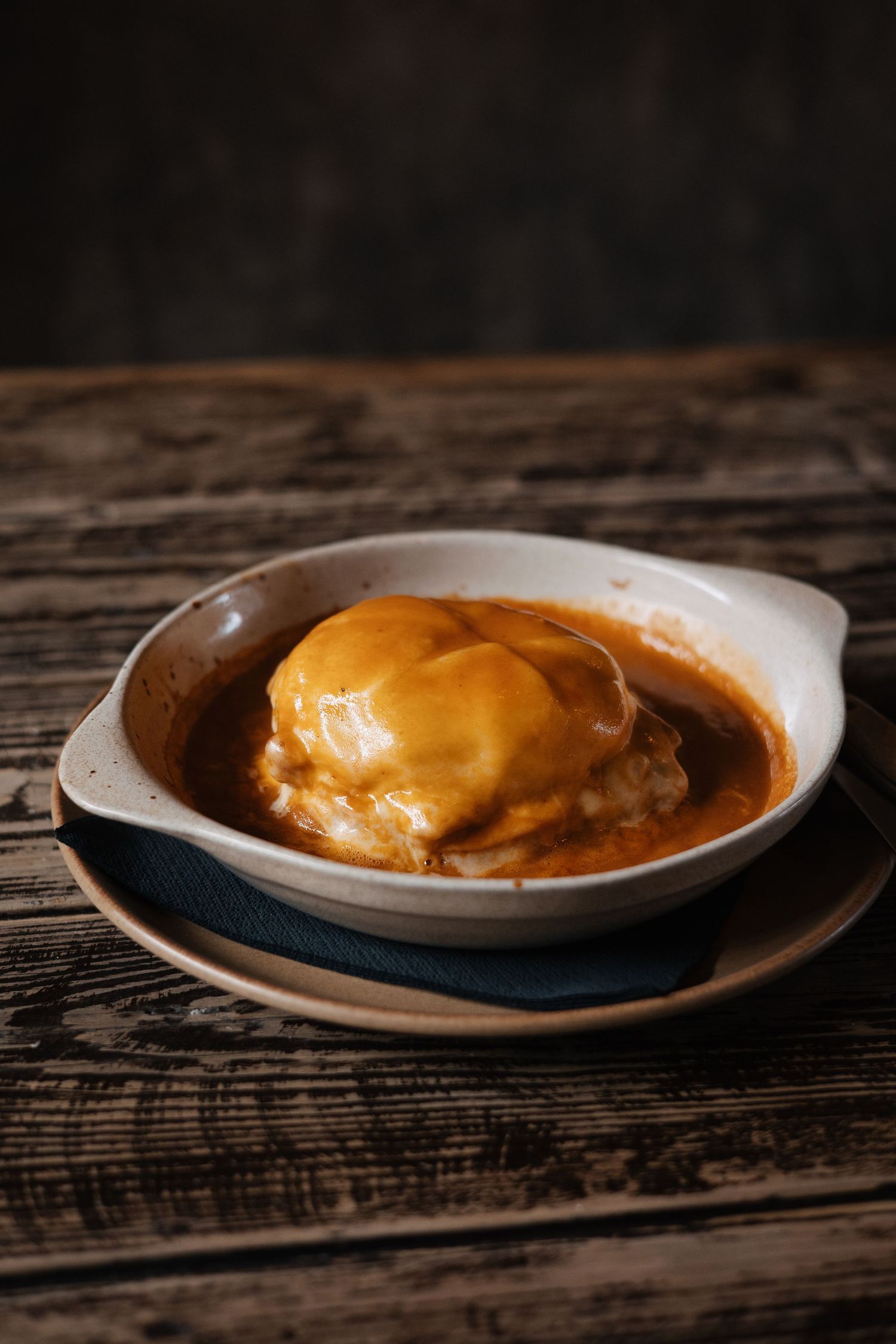 A golden-brown omurice dish served on a white plate against a rustic wooden surface.